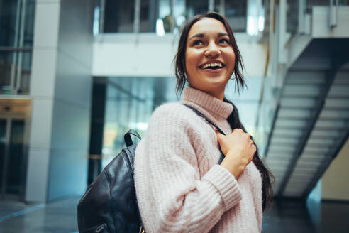 Smiling university student in campus. Happy girl in campus with bag looking over shoulder. - JLPSF06327