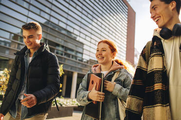 Mädchen, das mit Freunden in der Uni im Freien spazieren geht. Freunde in der Uni gehen nach dem Unterricht nach Hause. - JLPSF06332