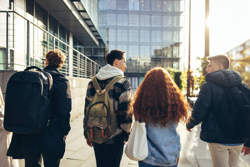 Gruppe von Studenten, die in der Schule im Freien spazieren gehen. Teenager mit ihren Taschen, die auf dem College-Campus spazieren gehen. - JLPSF06346