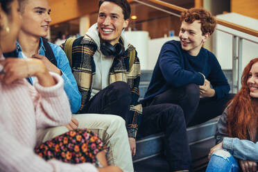 Lächelnde Studenten auf dem College-Campus sitzen. Gruppe von Männern und Frauen, die Spaß während der Pause Zeit in der Universität. - JLPSF06351