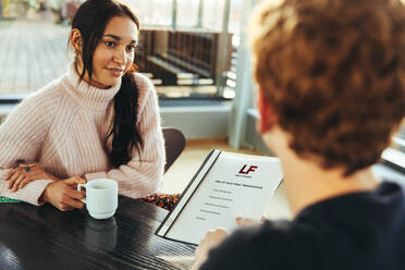 Student zeigt Abschlusspräsentation Datei zu Mädchen in der Schule. Mädchen hält Kaffee und hört zu Klassenkameraden in der Universität. - JLPSF06369