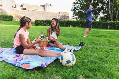 Mutter und Tochter unterhalten sich auf einer Picknickdecke sitzend - DMMF00156