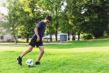 Junge spielt Fußball auf einer Wiese - DMMF00163