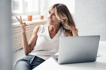 Businesswoman gesturing by laptop on desk at office - JOSEF14084