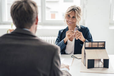 Lächelnder Immobilienmakler mit Blick auf einen Kunden im Büro - JOSEF14110