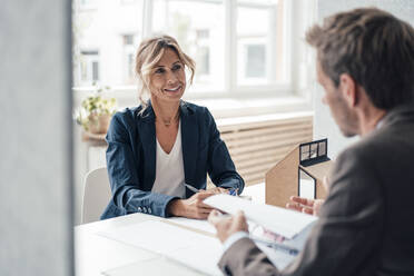 Immobilienmakler und Kunde besprechen sich im Büro - JOSEF14113