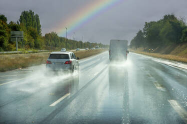 Frankreich, Normandie, Rouen, Verkehr auf nasser Autobahn mit Regenbogen im Hintergrund - FRF00980