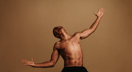 African american man standing on brown background with outstretched arms. Shirtless man with face up and open arms. - JLPSF06396