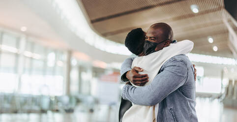 Ein afrikanisches Paar umarmt sich, nachdem es voneinander getrennt wurde. Ein männlicher Reisender umarmt seine Frau am Flughafen. - JLPSF06592