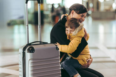 Mutter mit ihrem Kind auf dem Flughafen während einer Pandemie auf dem Flughafen. Eine Frau ist emotional, als sie ihren Sohn während des Ausbruchs von Covid-19 auf dem Flughafen trifft. - JLPSF06607
