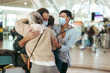 Senior woman meeting her family at airport arrival gate after pandemic. Man with family being greeted by grandmother at airport. - JLPSF06617