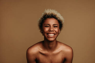 Lächelnde afroamerikanische Frau, isoliert auf braunem Hintergrund. - JLPSF06631