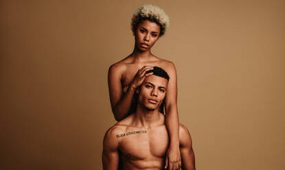 Porträt eines afroamerikanischen Paares, das die Black-Lives-Matter-Bewegung unterstützt. Eine lockige Frau steht hinter einem muskulösen Mann. - JLPSF06639