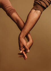Ein Paar, das nebeneinander steht und sich mit verschränkten Fingern an der Hand hält. Ein Ausschnitt zeigt die Einheit der beiden Hände. - JLPSF06650