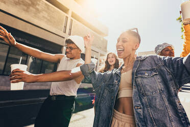 Junge Freunde, die fröhlich in der Stadt tanzen. Eine Gruppe von Freunden der Generation Z, die Spaß haben, während sie zusammen in der Sommersonne spazieren gehen. Glückliche junge Freunde, die zusammen in der Stadt abhängen. - JLPSF06766