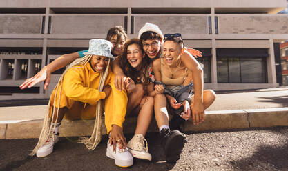 Making happy memories with friends. Group of generation z friends laughing cheerfully while hanging out together outdoors in the city. Happy young friends having fun together in the summer sun. - JLPSF06775