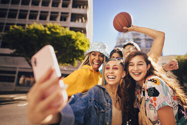 Eine Gruppe von Freunden macht ein Selfie im Freien. Fröhliche Freunde der Generation Z, die Spaß haben, während sie zusammen in der Stadt abhängen. Multiethnische junge Menschen, die ihre glücklichen Momente in der Sonne festhalten. - JLPSF06794