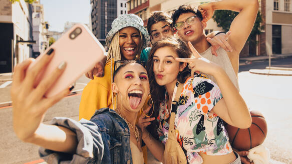 Lebendige Selfies. Eine Gruppe multiethnischer junger Menschen posiert für ein gemeinsames Selfie im Freien. Fröhliche Freunde der Generation Z haben Spaß und halten ihre glücklichen Momente in der Stadt fest. - JLPSF06797