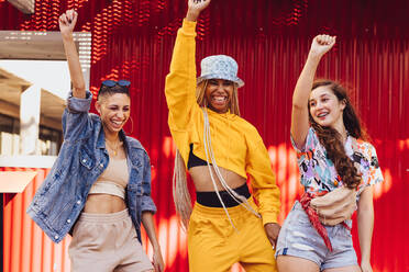 Female friends dancing and having fun. Three energetic young friends having a good time together outdoors. Group of multiethnic generation z friends making happy memories. - JLPSF06808