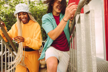 Happy young friends running up the stairs outdoors. Group of cheerful young people smiling and having a good time together. Multiethnic friends having fun and making happy memories. - JLPSF06817