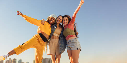 Female friends enjoying being together. Cheerful female youngsters smiling and having fun while standing together outdoors. Group of generation z friends making happy memories together. - JLPSF06841