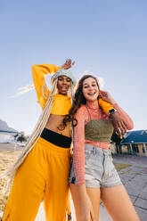 Two happy girls smiling at the camera while standing together outdoors. Two best friends having fun while hanging out together in the city. Female youngsters feeling vibrant and full of life. - JLPSF06855