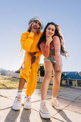 Two female youngsters making gestures while standing together outdoors. Two generation z friends having fun in the city. Female best friends feeling vibrant and full of life. - JLPSF06857