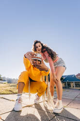 Girl making a frame gesture with her hands while looking at the camera. Two female best friends friends having fun together outdoors in the city. Happy female youngsters feeling vibrant. - JLPSF06860