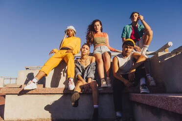 Group of friends sitting together outdoors in the sun. Multiethnic youngsters spending quality time together in the city. Group of generation z friends chilling outdoors. - JLPSF06862