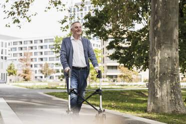 Lächelnder älterer Mann mit Gehhilfe auf dem Gehweg - UUF27545