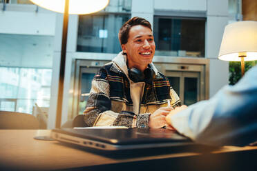 Ein junger Mann diskutiert mit einem Mitschüler in der Universitätsbibliothek. - JLPSF06993