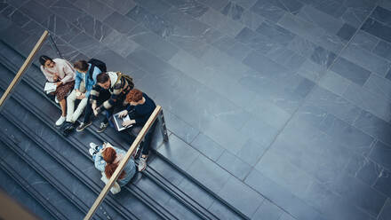 Blick auf Studenten, die auf einer Treppe sitzen und über ihre Studien diskutieren. Junge Leute studieren auf dem Campus. - JLPSF07006
