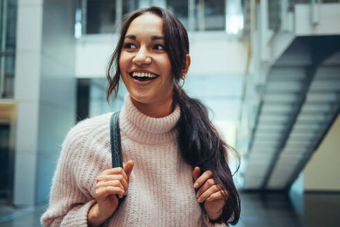 Happy female student going for class. Young woman smiling in college campus. - JLPSF07012