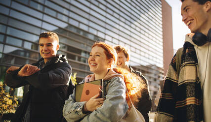 Gruppe junger Leute, die auf dem Schulgelände spazieren gehen. Glückliche Studenten, die gemeinsam auf dem College-Campus spazieren gehen. - JLPSF07026