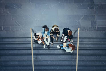 Blick von oben auf Studenten, die auf einer Treppe im College sitzen. Junge Leute auf dem Highschool-Campus. - JLPSF07069