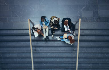 Junge Leute in der Universität sitzen auf den Stufen und studieren. Studenten sitzen auf dem Campus. - JLPSF07070