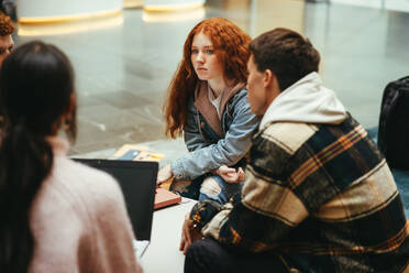 Studenten, die in der College-Lobby sitzen und diskutieren. Teenager, die gemeinsam ein Projekt in der Hochschule durchführen. - JLPSF07073