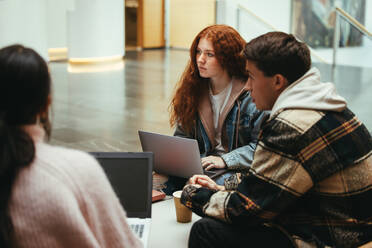 Eine Gruppe von Studenten diskutiert über das Studium am College. Freunde auf dem College-Campus mit Laptop. - JLPSF07075