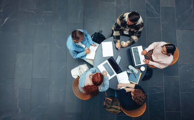 Draufsicht auf eine Gruppe von Studenten, die zusammen an einem Tisch sitzen und in einer Gruppe lernen. - JLPSF07082