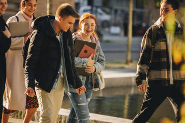 Fröhliche Studenten, die zusammen draußen im College spazieren gehen. Jungen und Mädchen auf dem Universitätscampus. - JLPSF07099