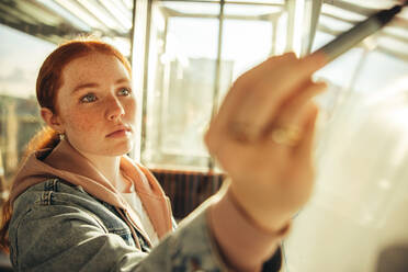 Studentin schreibt am Whiteboard im College. Junge Frau studiert am Whiteboard in der Universität. - JLPSF07103