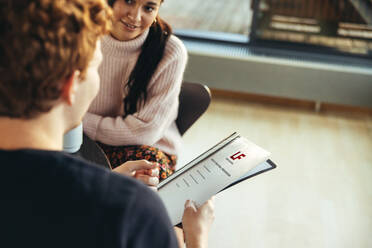 Zwei Studenten besprechen eine Projektmappe im College. Mädchen und Junge studieren ein Projekt an der Universität. - JLPSF07112