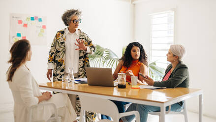 Verschiedene Geschäftsfrauen diskutieren während einer Sitzung. Eine Gruppe von Unternehmerinnen tauscht in einem Sitzungssaal kreative Ideen aus. Multikulturelle Geschäftsfrauen arbeiten in einem reinen Frauen-Startup zusammen. - JLPSF07199