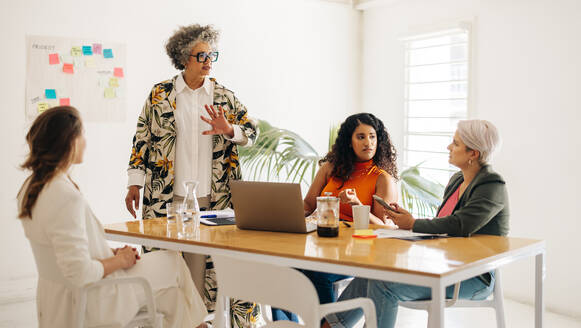 Verschiedene Geschäftsfrauen diskutieren während einer Sitzung. Eine Gruppe von Unternehmerinnen tauscht in einem Sitzungssaal kreative Ideen aus. Multikulturelle Geschäftsfrauen arbeiten in einem reinen Frauen-Startup zusammen. - JLPSF07199