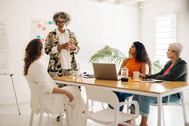 Teamleiterin bei einer Besprechung mit ihren Kolleginnen. Gruppe von Geschäftsfrauen, die in einem Sitzungssaal kreative Ideen austauschen. Verschiedene Geschäftsfrauen, die in einem reinen Frauen-Startup zusammenarbeiten. - JLPSF07200