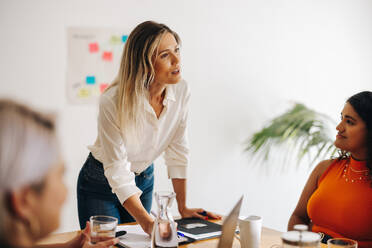 Junge Teamleiterin beim Brainstorming mit ihren Kolleginnen in einem Büro. Gruppe multikultureller Geschäftsfrauen bei einer Besprechung in einem Sitzungssaal. Kreative Geschäftsfrauen, die in einem rein weiblichen Startup zusammenarbeiten. - JLPSF07211