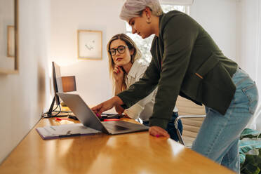 Geschäftspartnerinnen bei einer Besprechung in einem modernen Büro. Zwei Unternehmerinnen arbeiten im Team in einem von Frauen geführten Unternehmen an einem Laptop. - JLPSF07292