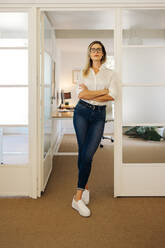 Confident young businesswoman looking at the camera while standing in front of her office. Successful businesswoman working in a creative workplace. - JLPSF07295