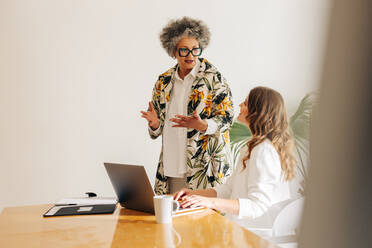 Zwei unterschiedliche Geschäftsfrauen bei einer Diskussion in einem modernen Besprechungsraum. Kreative Geschäftsfrauen arbeiten gemeinsam an einer neuen Aufgabe in einem von Frauen geführten Start-up-Unternehmen. - JLPSF07334