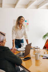 Zufriedene Teamleiterin bei einer Besprechung mit ihren Kolleginnen in einem Büro. Gruppe kreativer Geschäftsfrauen beim Brainstorming in einem Sitzungssaal. Verschiedene Geschäftsfrauen arbeiten in einem reinen Frauen-Startup zusammen. - JLPSF07343